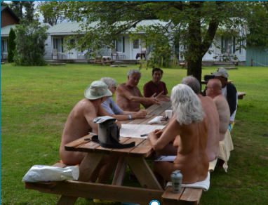 Naturistes discutant sur des tables à pic-nic