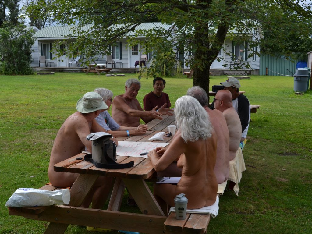 Naturistes discutant sur des tables à pic-nic lors d'une activité