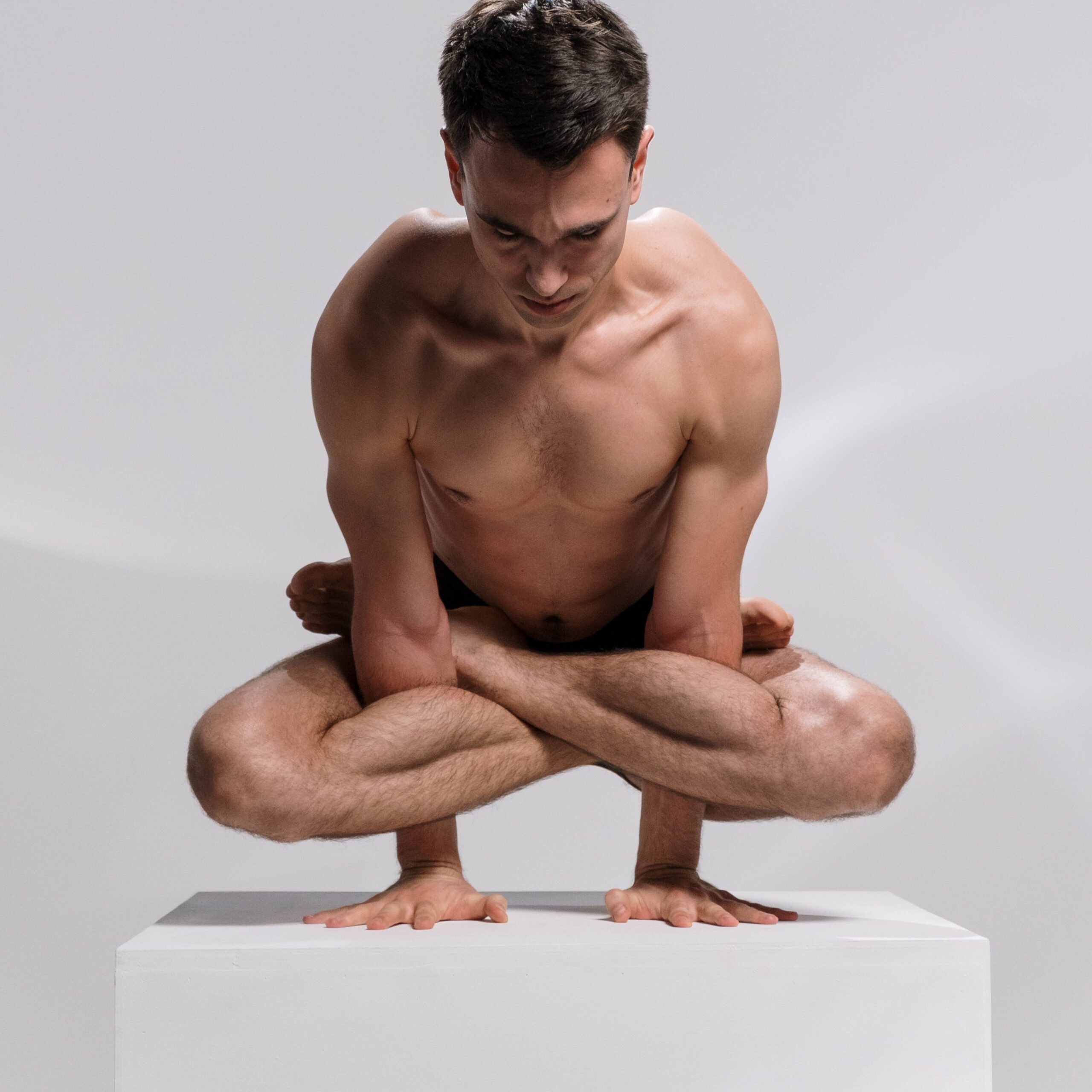 Homme faisant du yoga sur un cube blanc